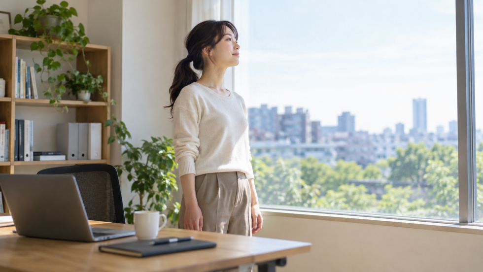 デスクから立ち上がり窓際で休憩する女性のAI生成イメージ
