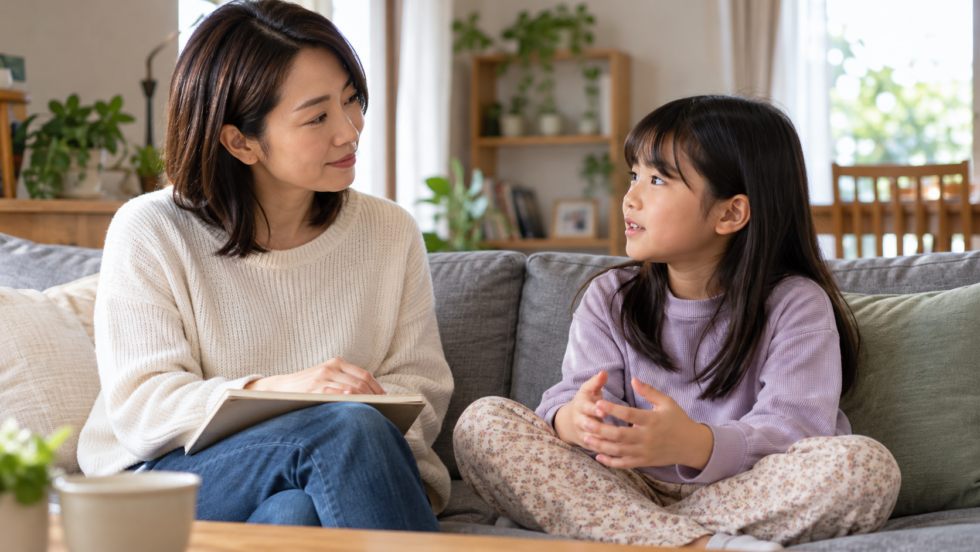 ソファで子どもの話を聞き、ノートを持つ保護者の説明用イメージ